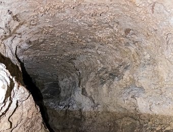 Vue de la grotte et du ruisseau  On peut noter sur la paroi le niveau maximum atteint par le ruisseau en période de hautes eaux