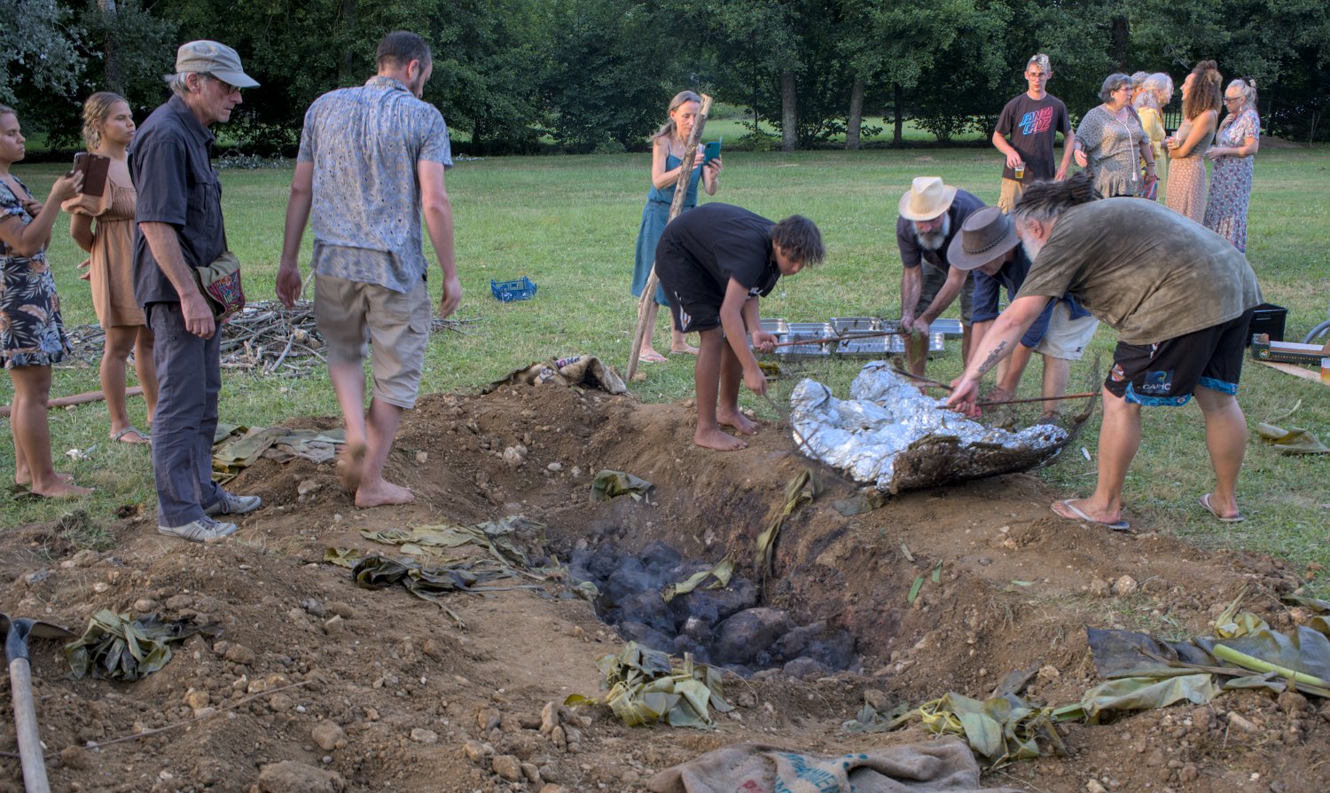 Récupération des poulets. Au fond du trou les pierres chaudes qui ont permis la cuisson